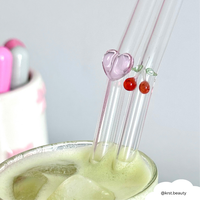 Pink heart-shaped glass straws from Coconut Lane in an iced green drink, with markers in a holder in the background.