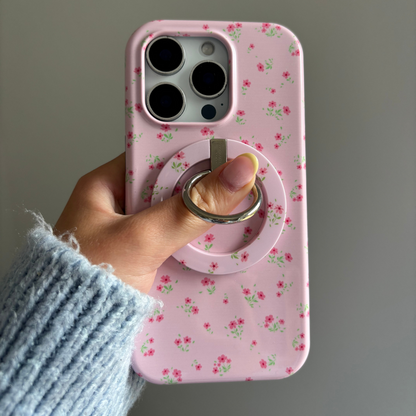 Hand holding a phone with a pink floral Coconut Lane MAGSAFE® Phone Ring, shown against a plain background.